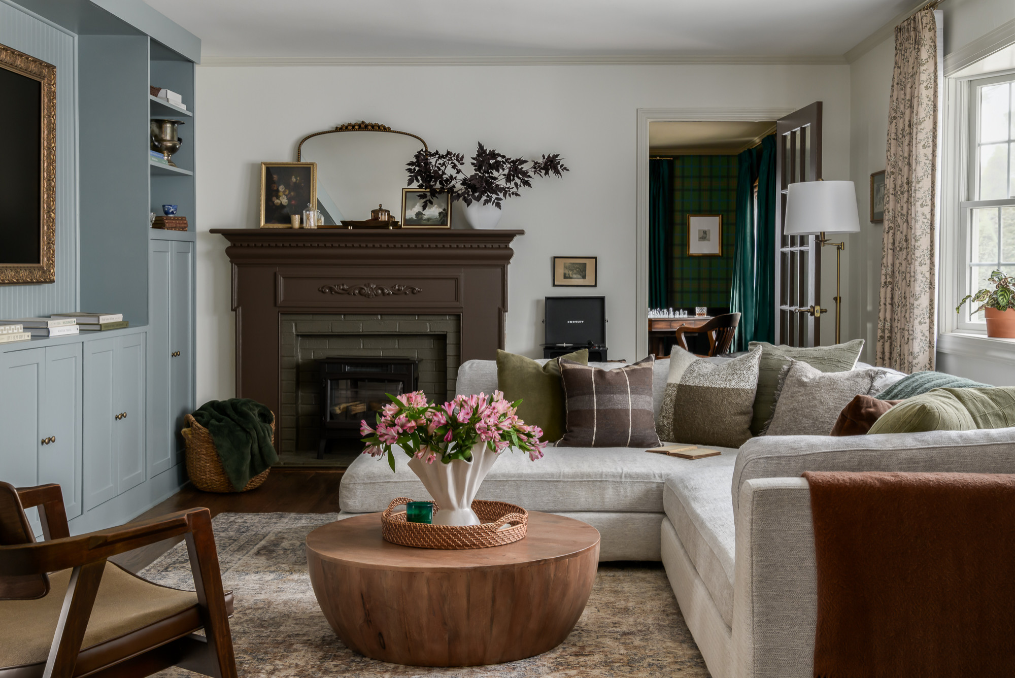 Living room with soft blue built-ins and a dark carved fireplace in a colonial home tour