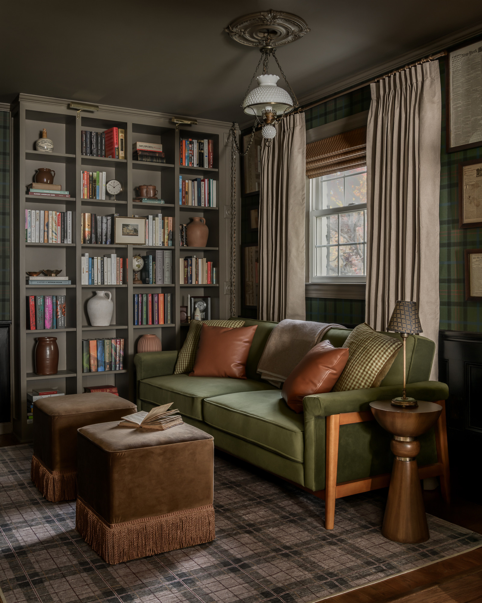 Library with olive velvet sofa and floor-to-ceiling bookshelves in a colonial home tour