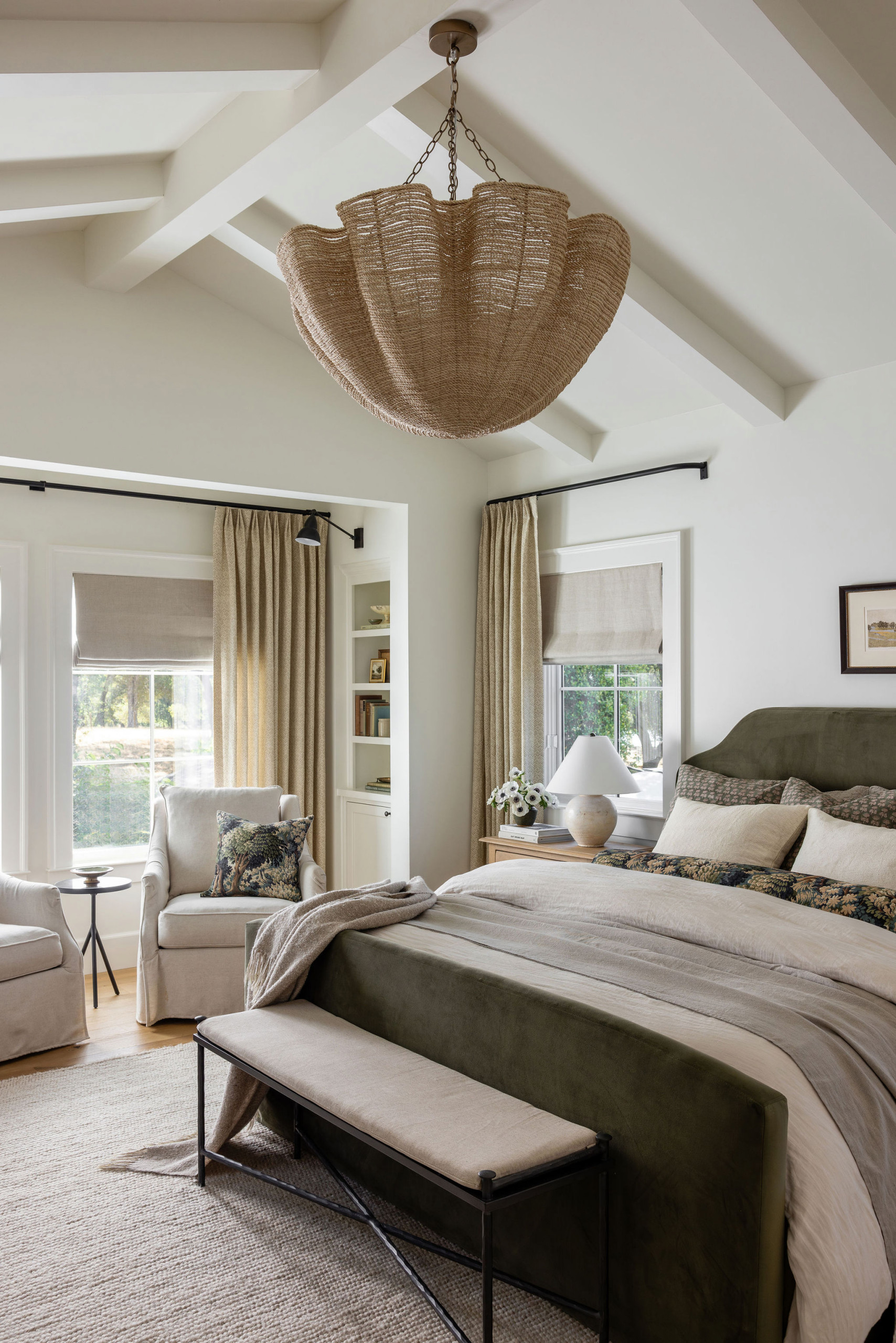 Primary bedroom with olive green upholstered bed and layered linen bedding in a traditional home tour