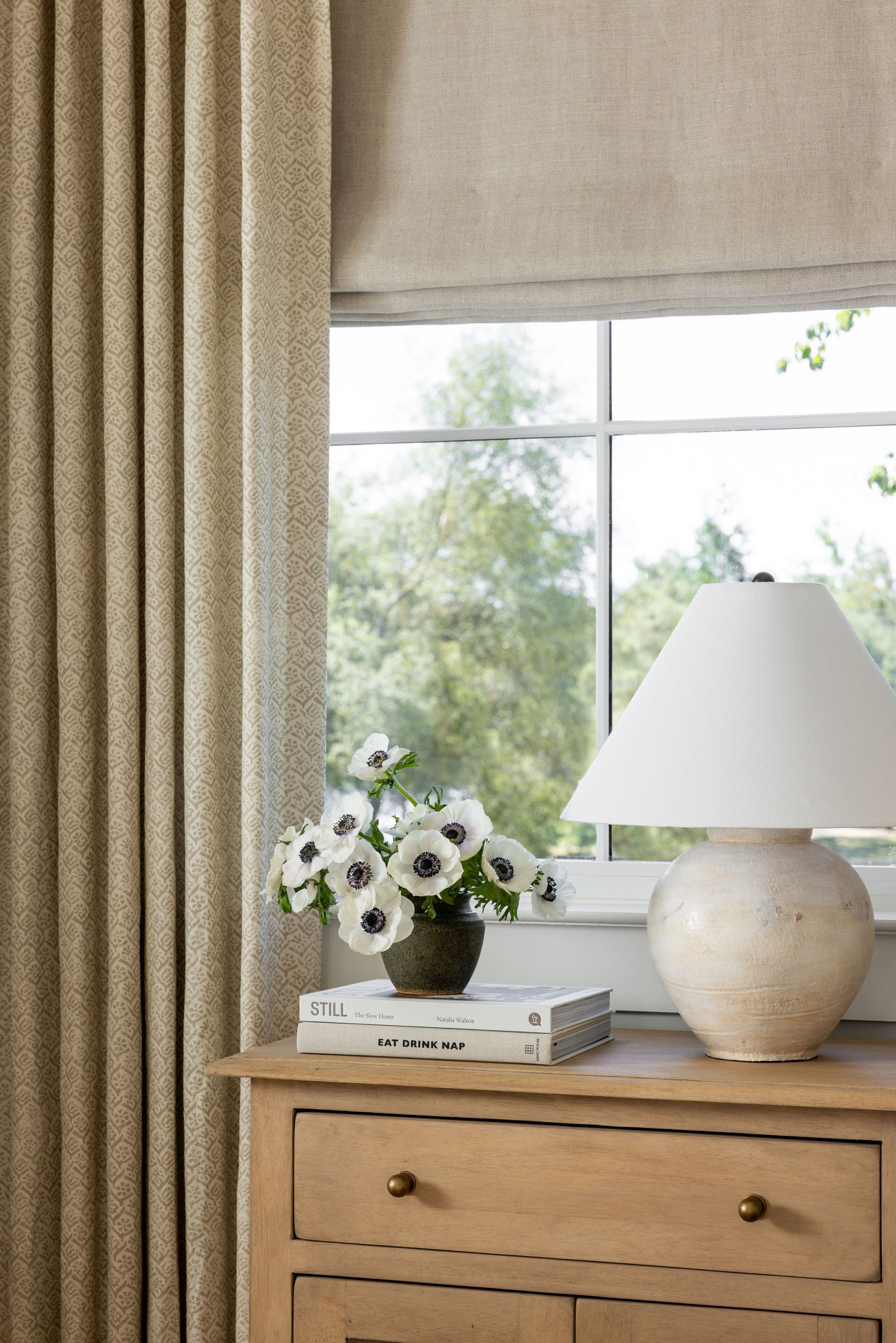 Primary bedroom with olive green upholstered bed and layered linen bedding in a traditional home tour