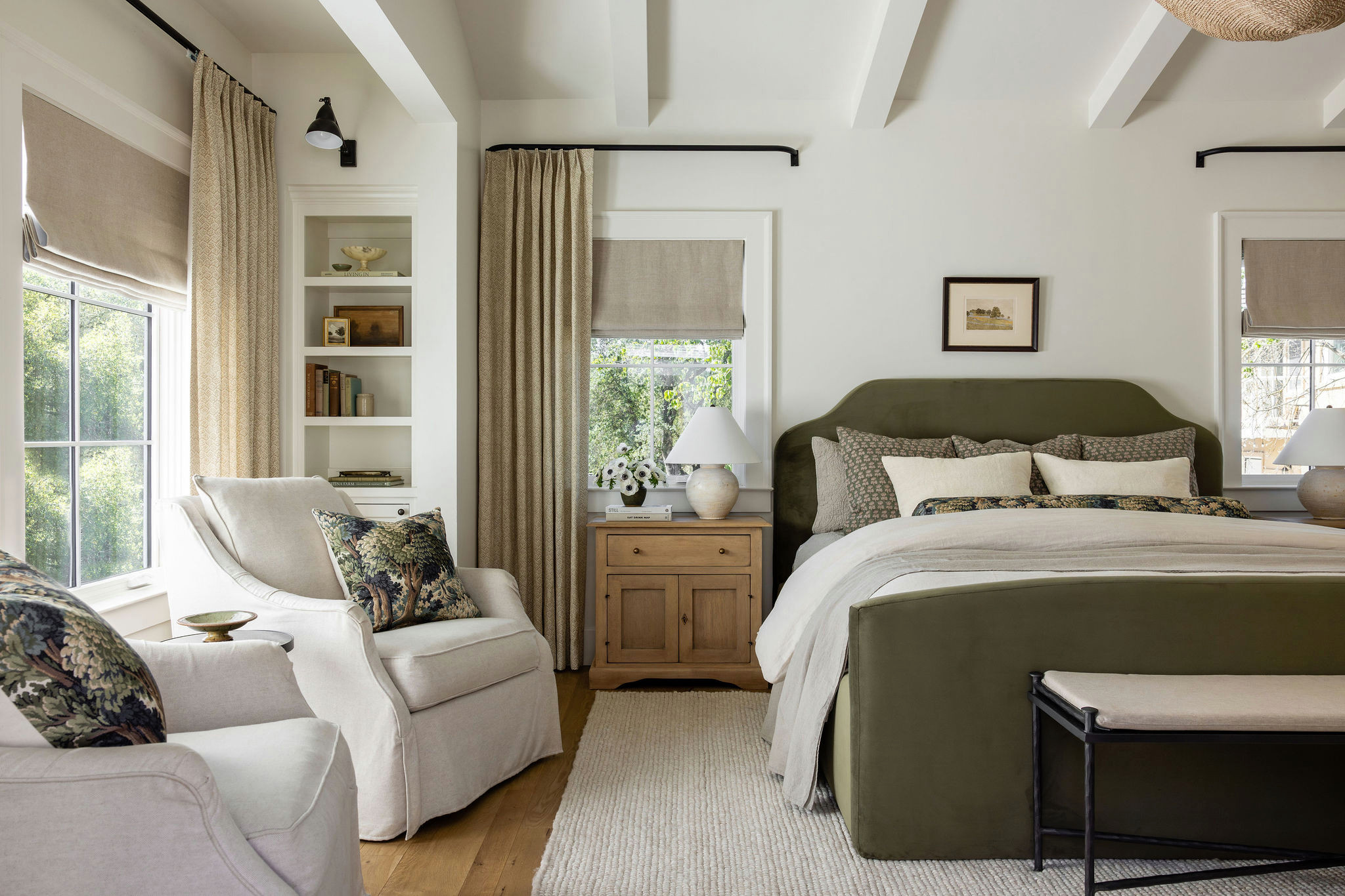 Primary bedroom with olive green upholstered bed and layered linen bedding in a traditional home tour