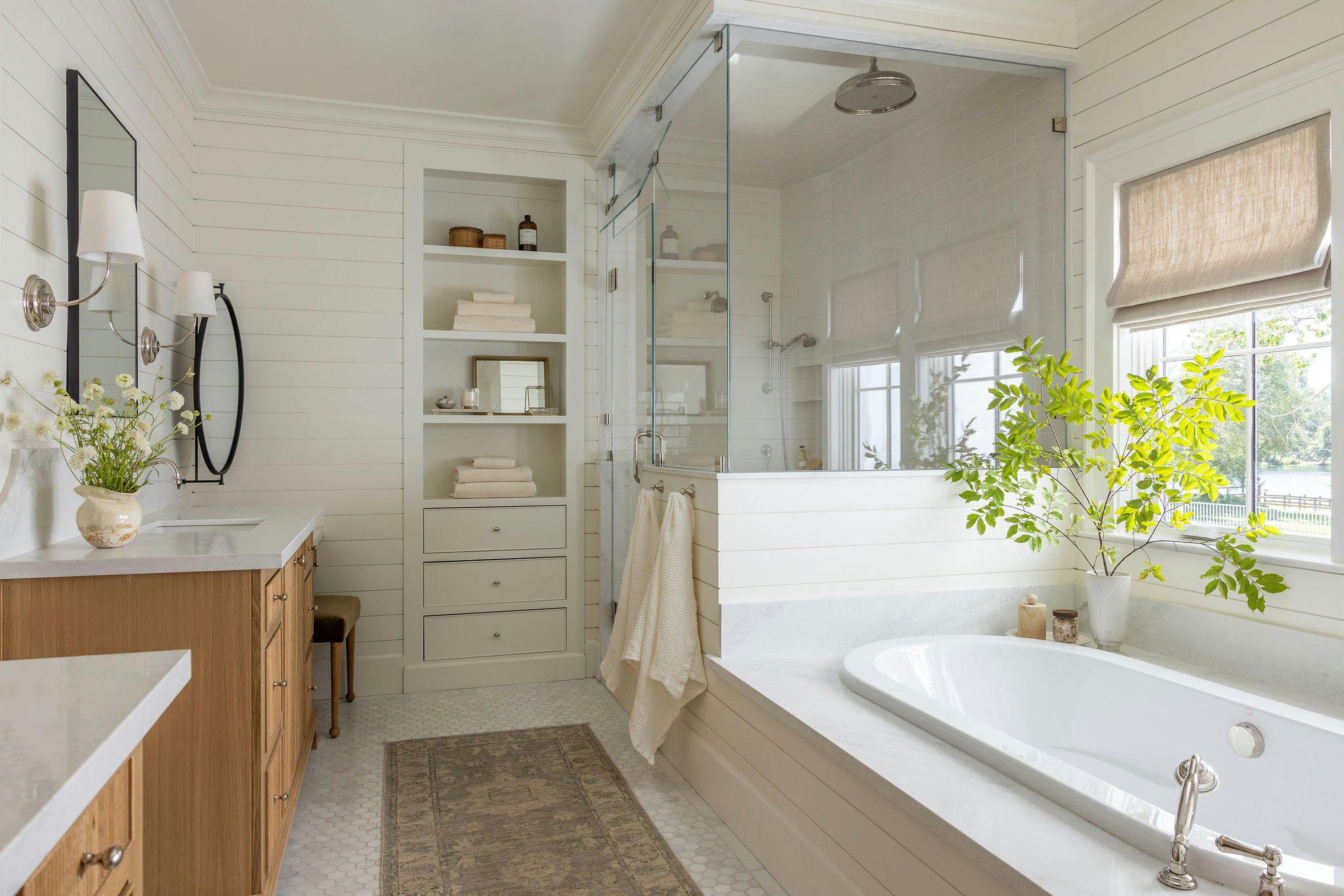 Primary bathroom with oak vanity and tub under the window in a traditional home tour