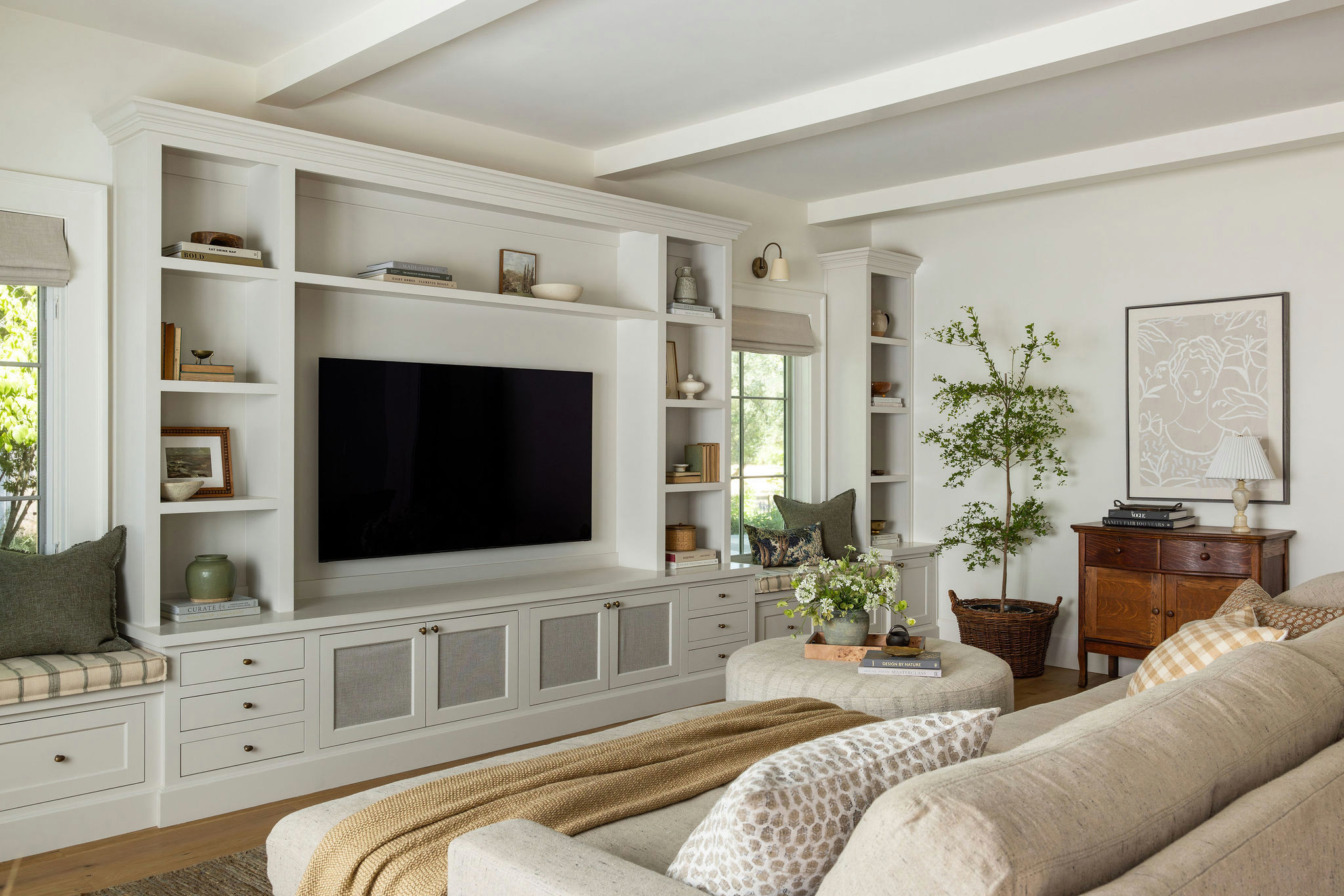 Family room with painted media wall built-ins and cream sofa in a traditional home tour