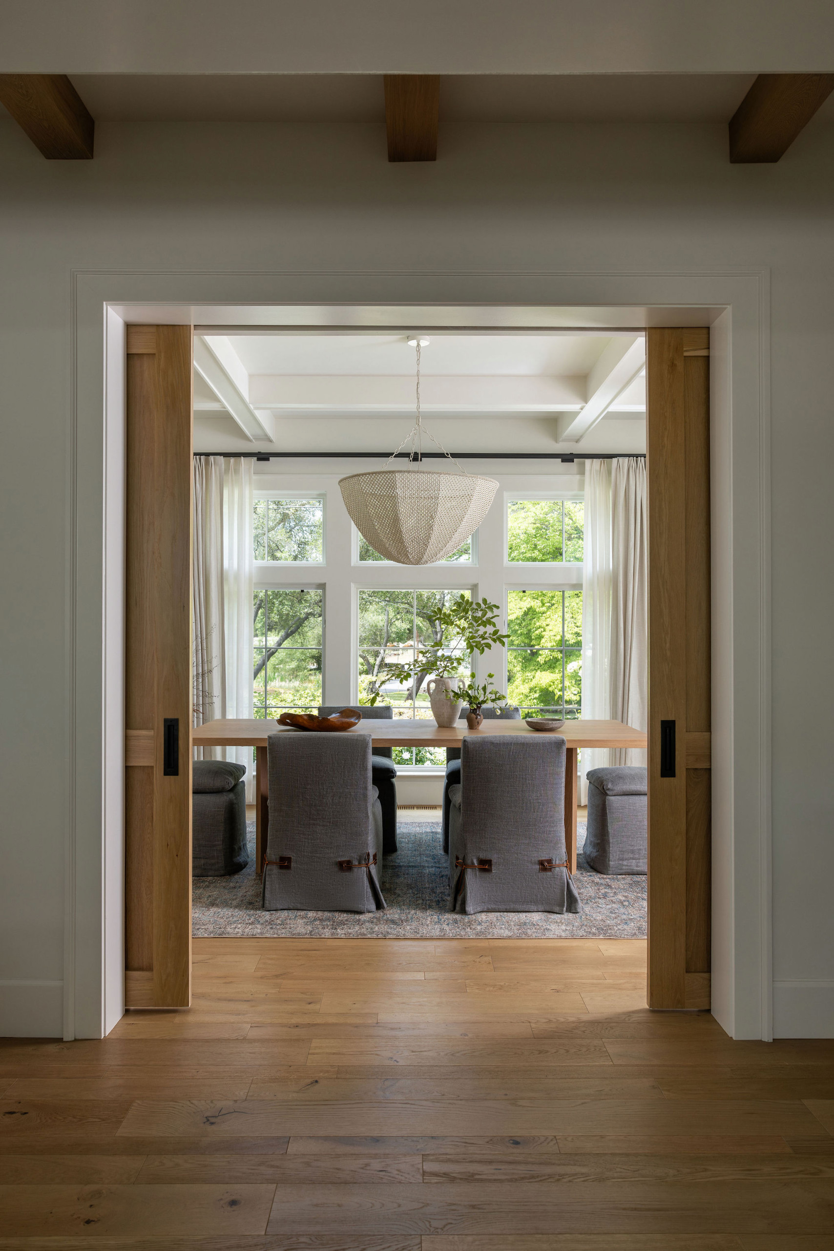 Formal dining room with woven dome chandelier and oak pocket doors in a traditional home tour
