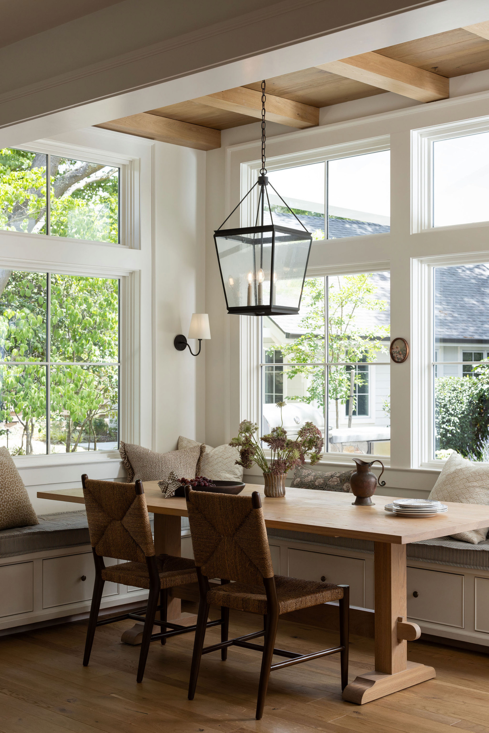 Breakfast nook with built-in window seat and black lantern pendant in a traditional home tour