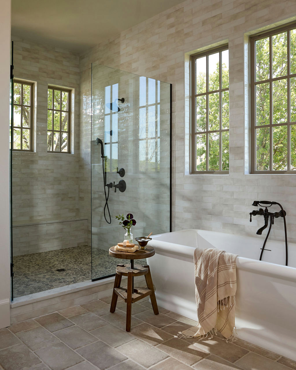 Mountain home tour primary bathroom with a freestanding tub under grid windows and beige glazed tile.