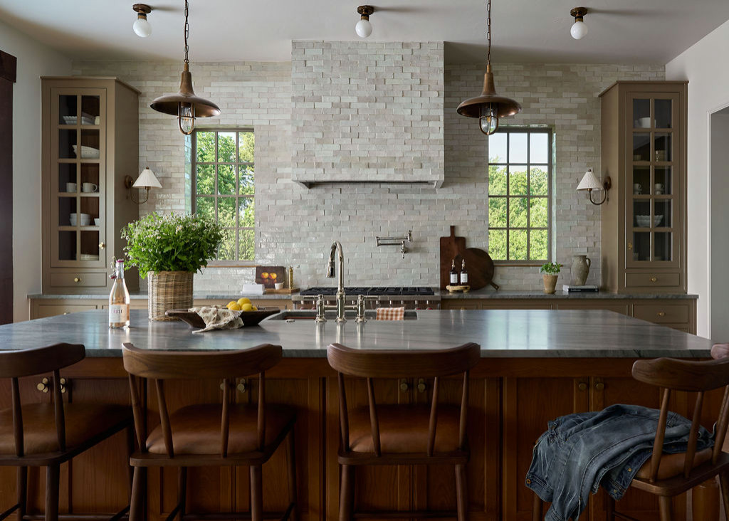 Mountain home tour kitchen with handmade-look tile walls and hood, an oak island, and brass pendants.