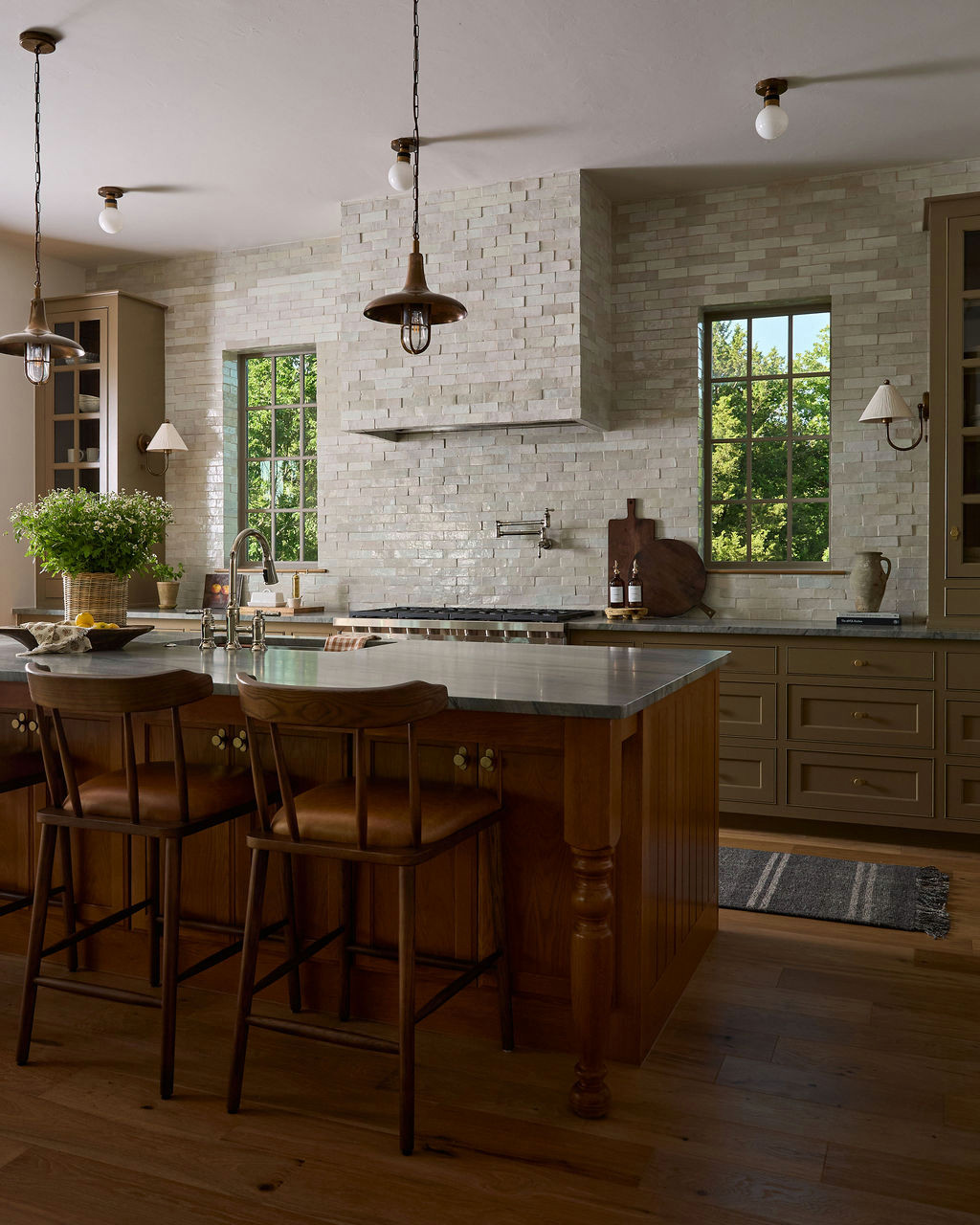 Mountain home tour kitchen with handmade-look tile walls and hood, an oak island, and brass pendants.
