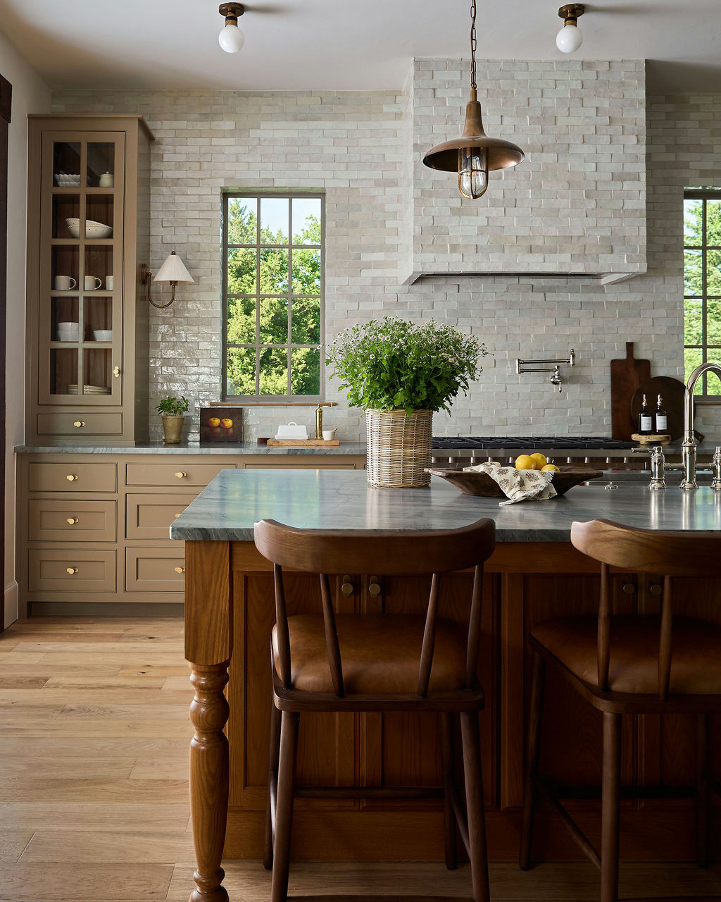 Mountain home tour kitchen with handmade-look tile walls and hood, an oak island, and brass pendants.