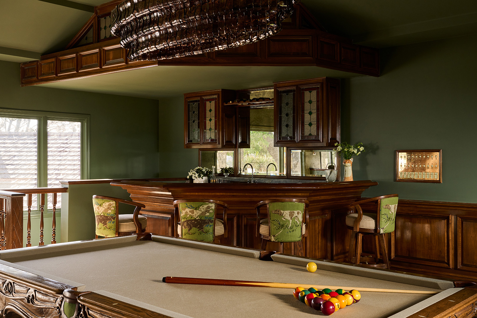 Family room with a stacked limestone fireplace and cognac leather swivel chair in a Mediterranean home tour