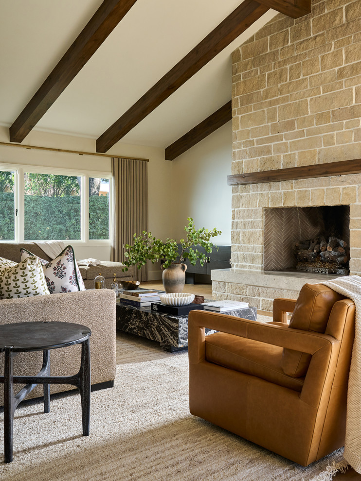 Living room with folk art portraits and a white hooded fireplace in a Mediterranean home tour
