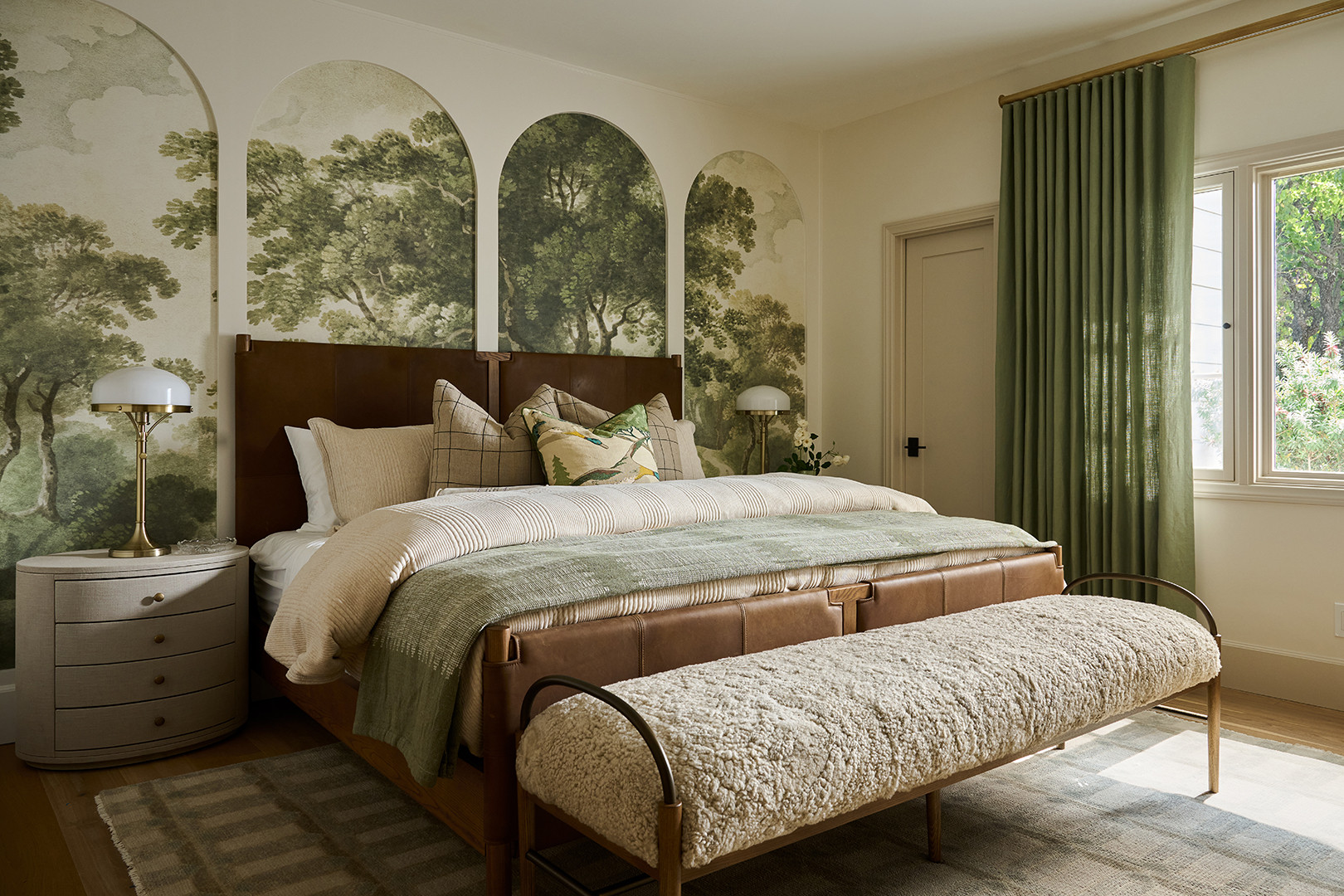 Bedroom with an arched landscape mural and leather bed in a Mediterranean home tour