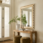 Entryway with a scalloped gold mirror and wavy burl wood console in a Mediterranean home tour