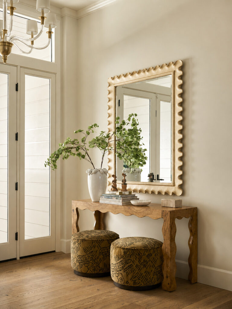Entryway with a scalloped gold mirror and wavy burl wood console in a Mediterranean home tour