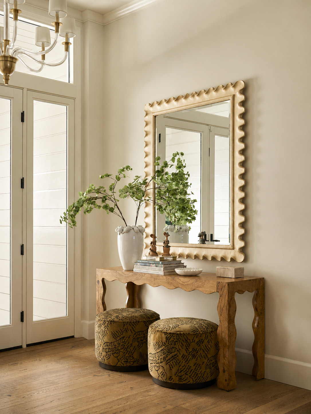 Entryway with a scalloped gold mirror and wavy burl wood console in a Mediterranean home tour