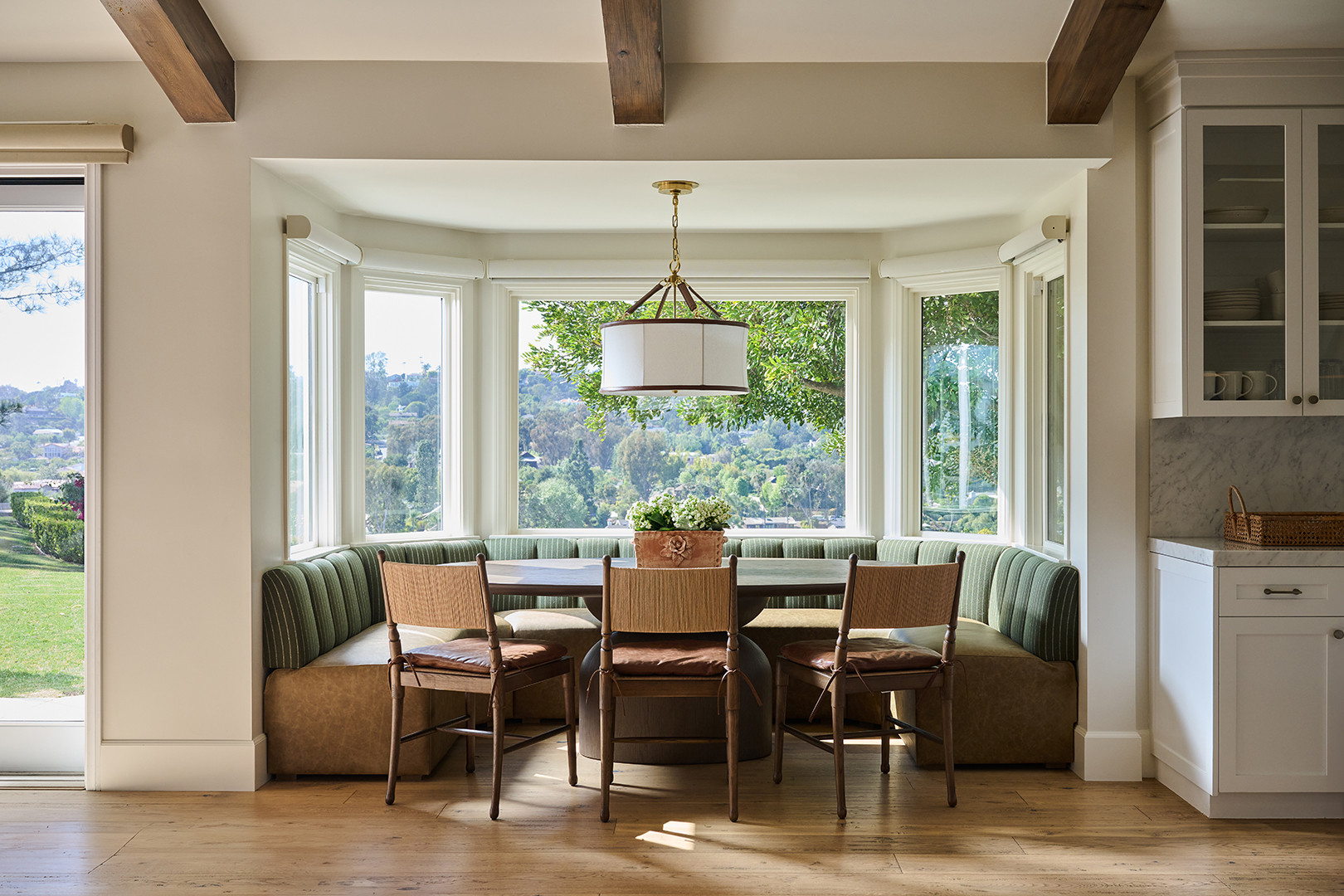 Breakfast nook with a striped banquette and leather-trimmed pendant in a Mediterranean home tour