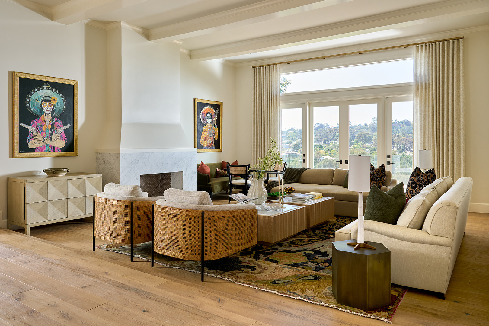 Living room with folk art portraits and a white hooded fireplace in a Mediterranean home tour