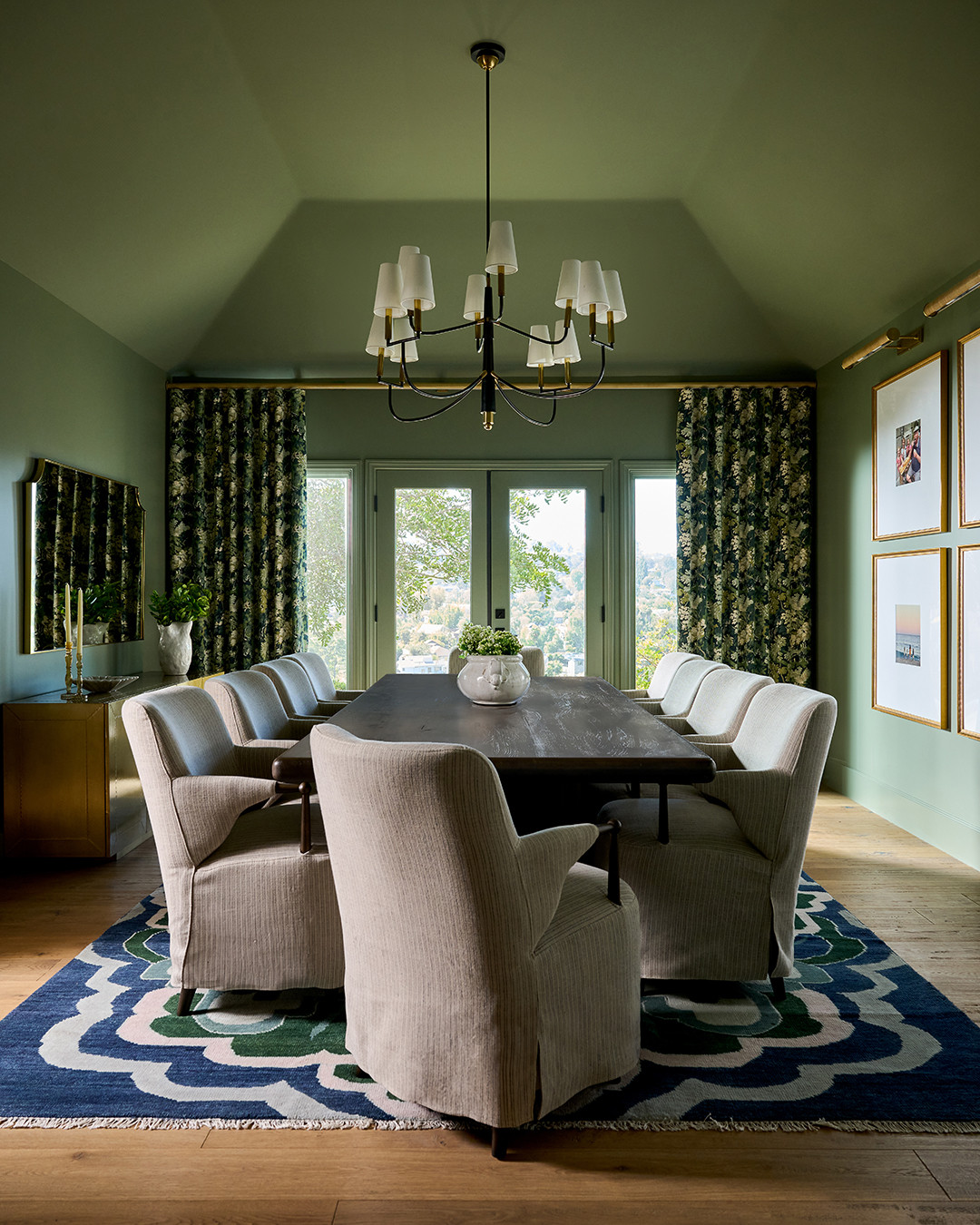 Dining room with green walls and ceiling and a scalloped rug in a Mediterranean home tour